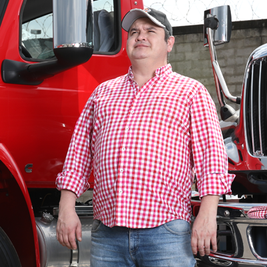 Juan Rueda parado frente a dos camion