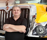 Juan Rueda con los brazos cruzados en frente de un camión INTERNATIONAL® amarillo